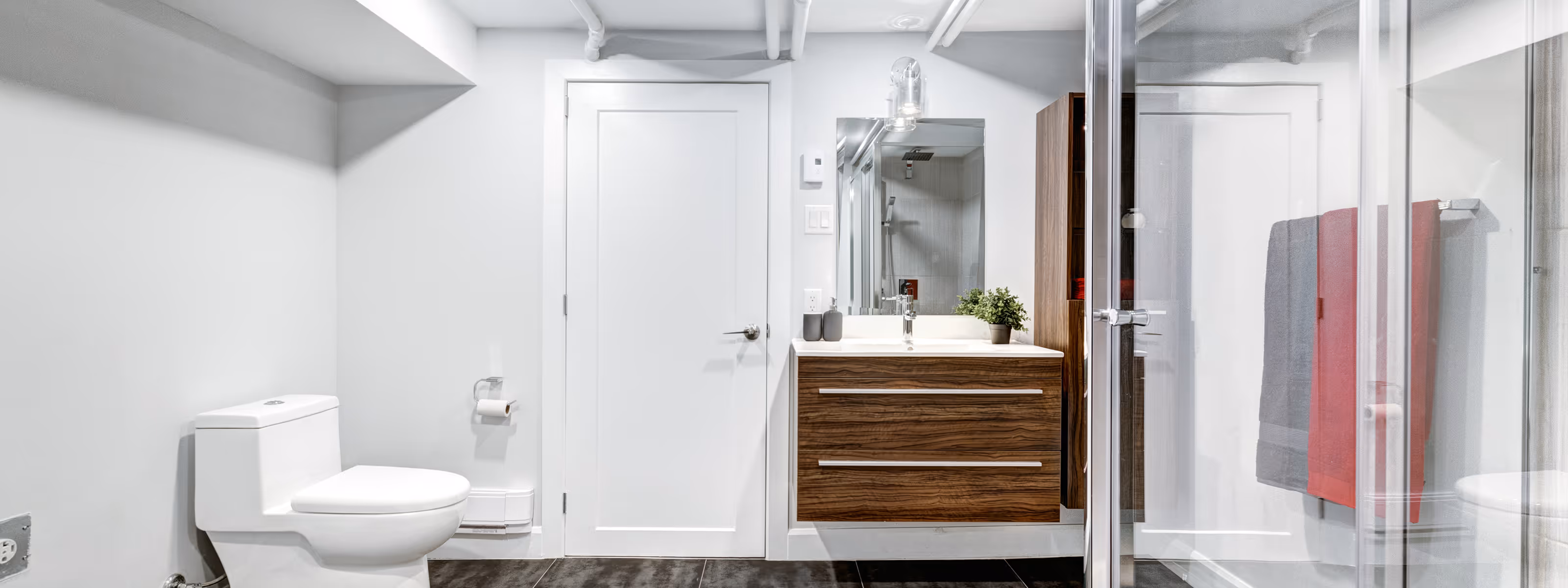 Contemporary basement bathroom remodel with floating wood vanity and glass shower