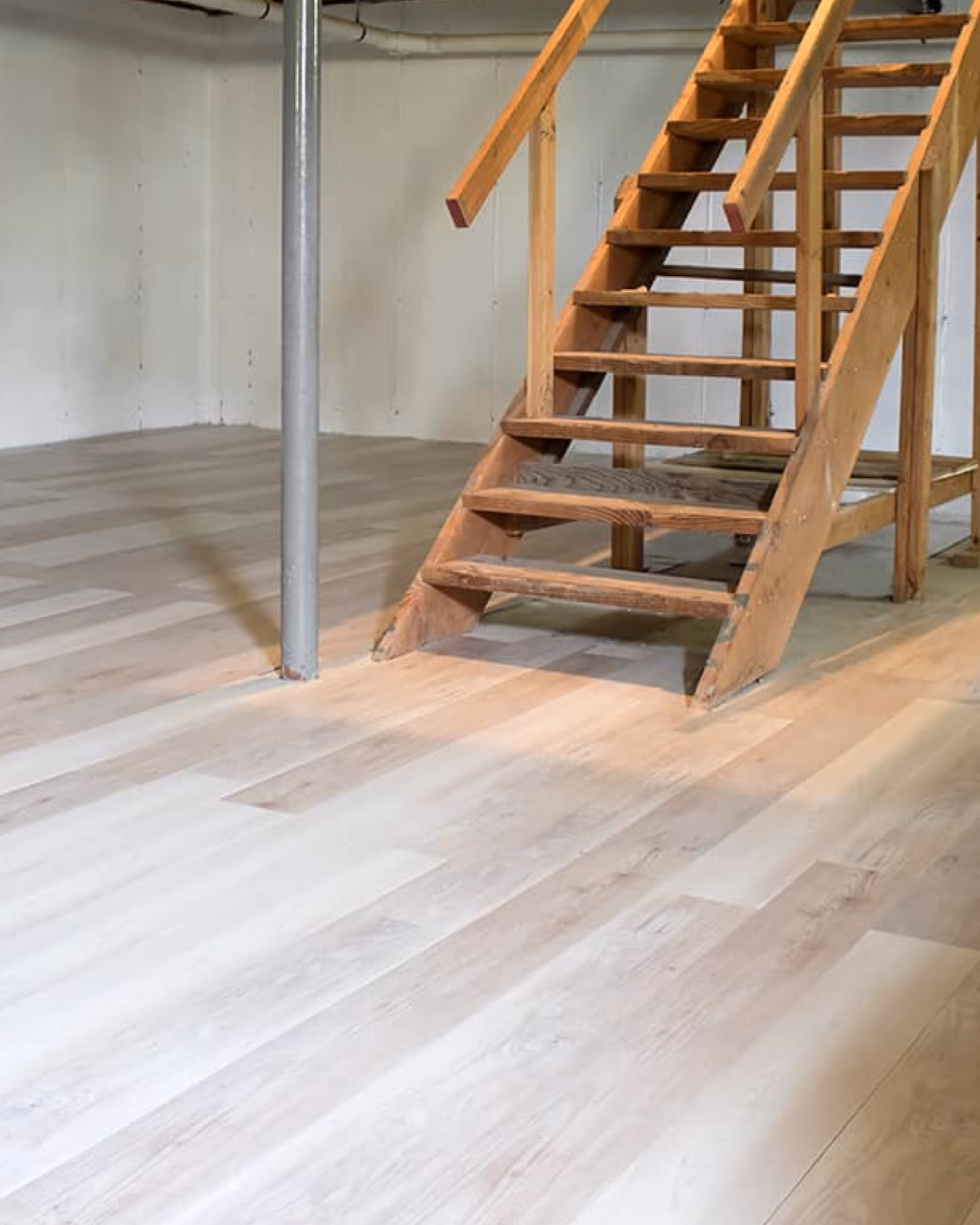 Light vinyl plank flooring installed in unfinished basement space