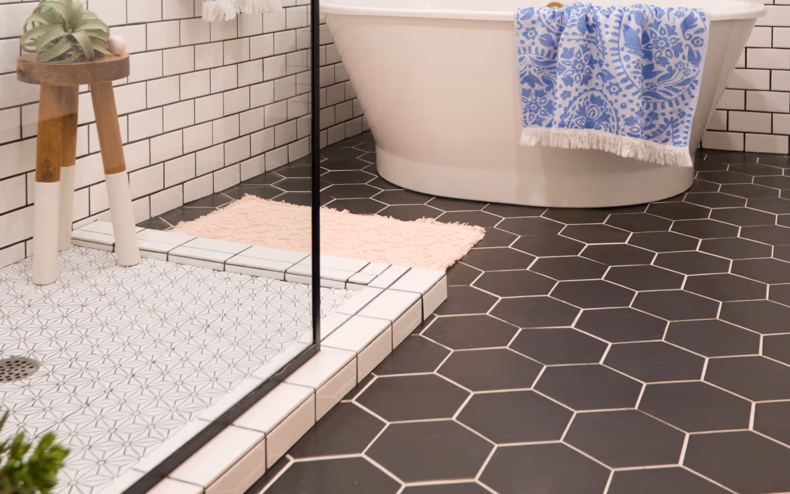 Bathroom flooring with black hex tile and walk-in shower base with subway wall tile