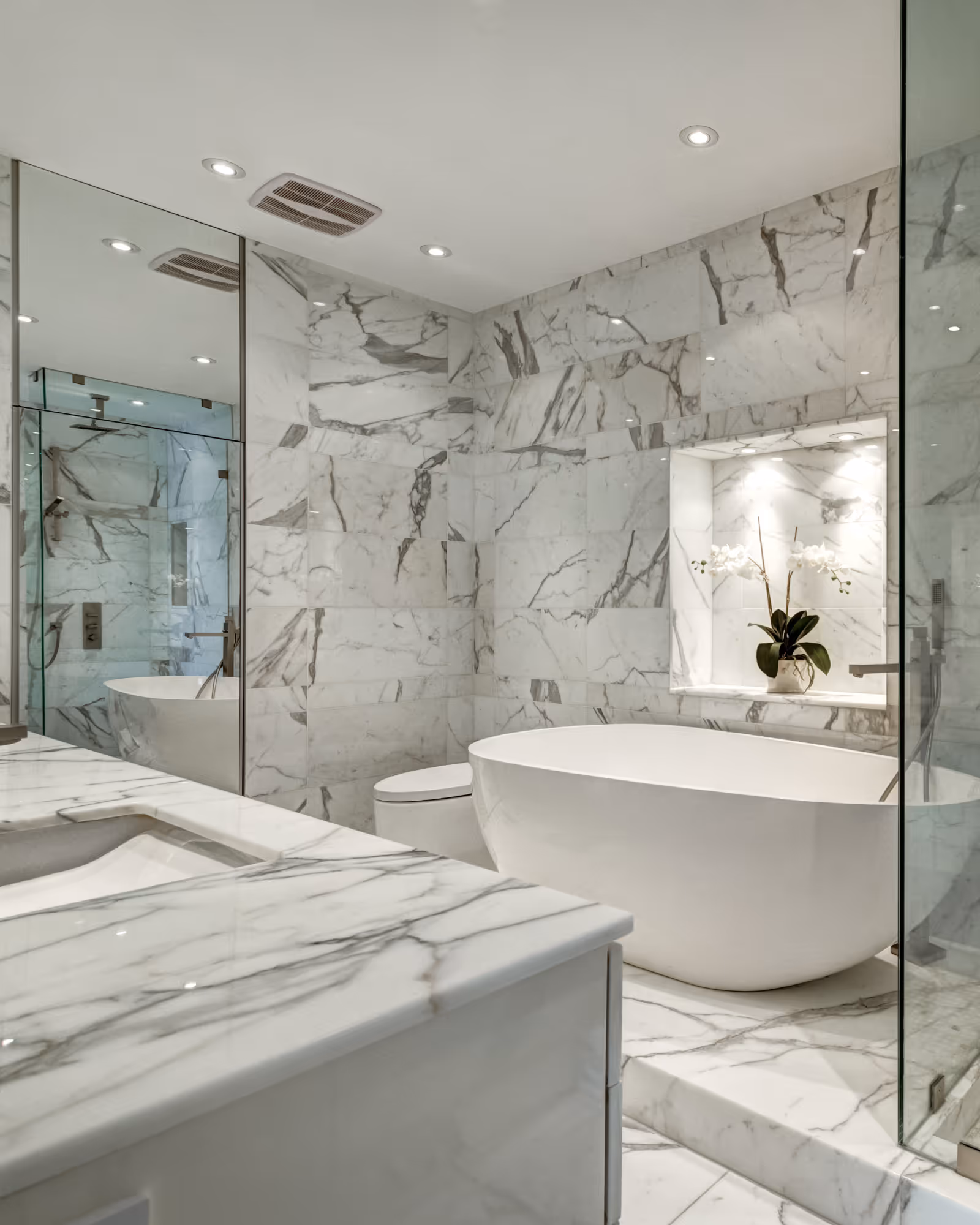 Luxury bathroom renovation with marble wall tile, freestanding tub, and glass shower