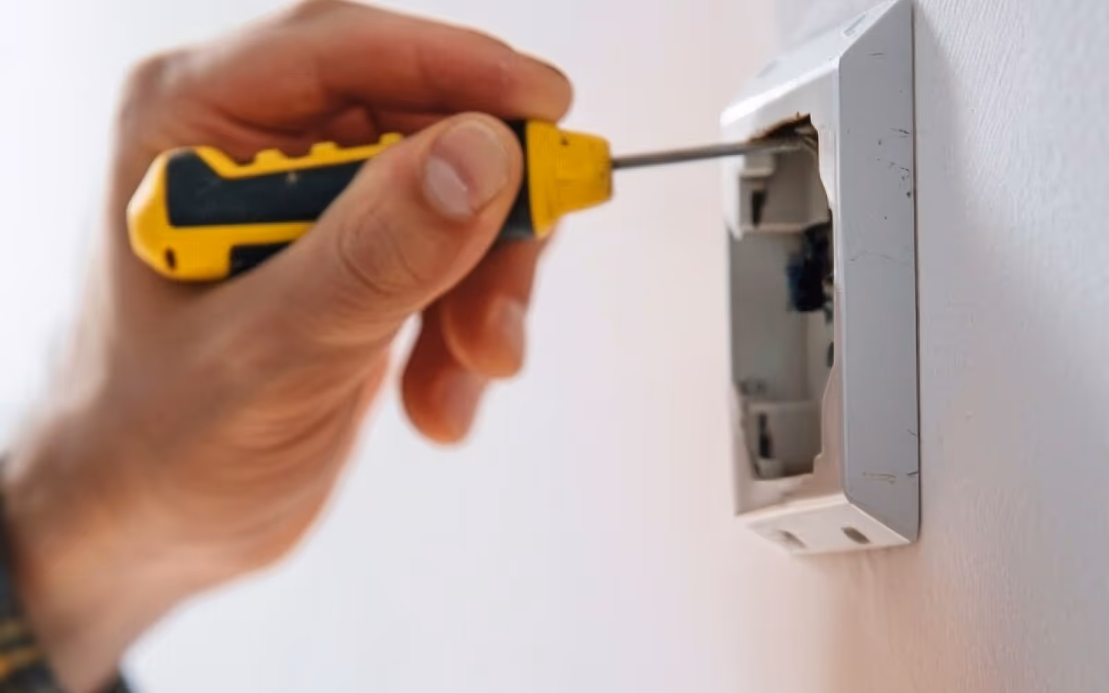 Handyman electrical service: tightening a wall switch or outlet box with a screwdriver