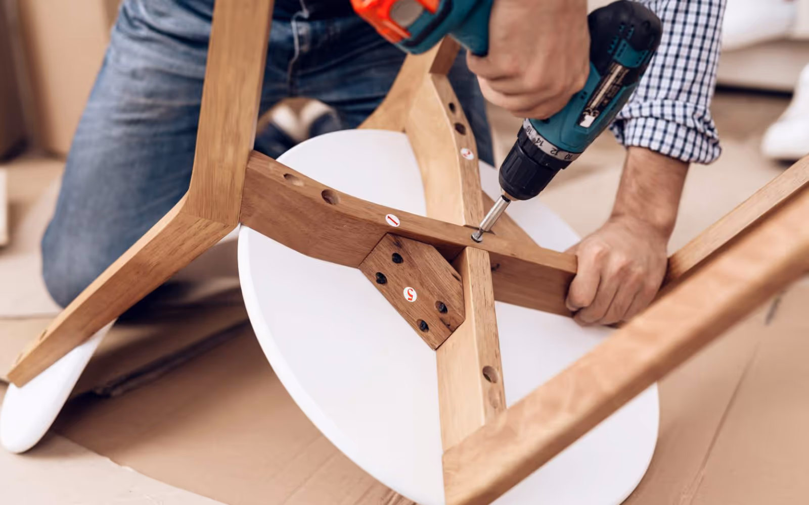 Furniture assembly service: handyman using a drill to assemble a wooden stool