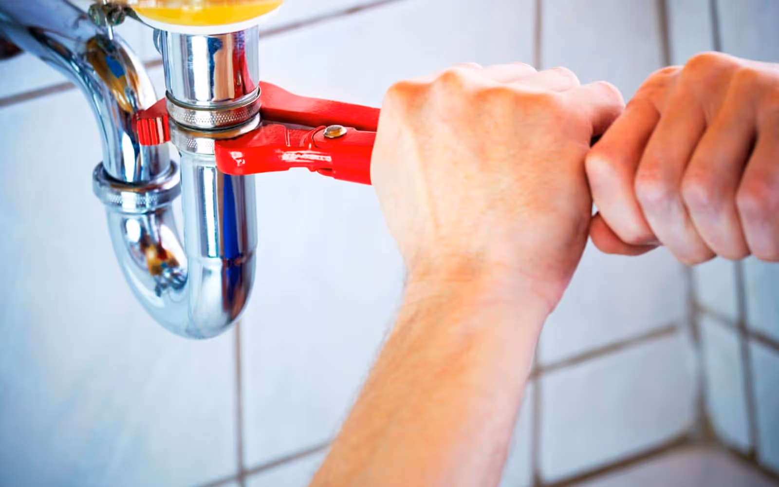 Handyman plumbing repair: tightening a sink drain trap with a pipe wrench