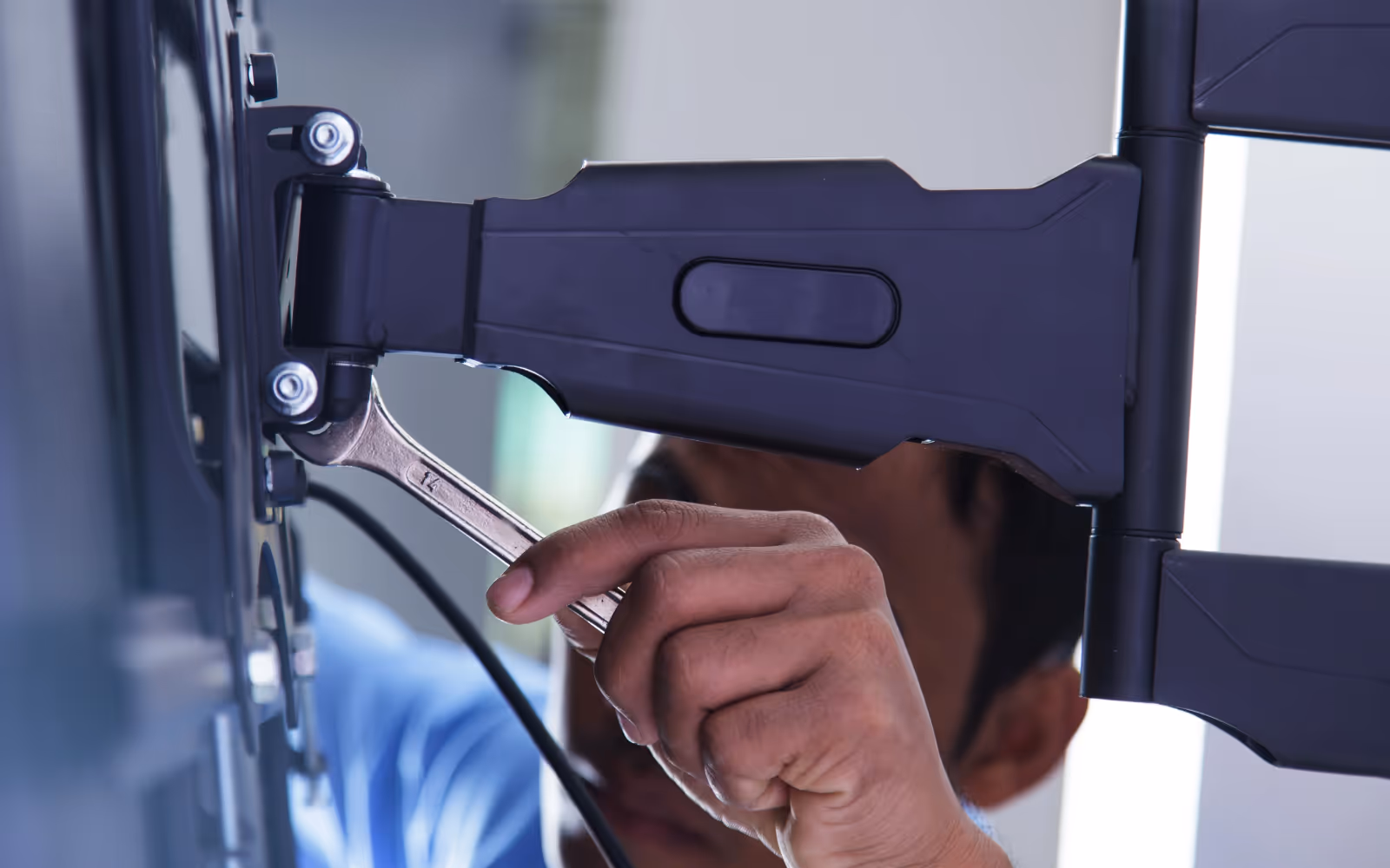 TV mounting service: adjusting a wall mount bracket with a wrench
