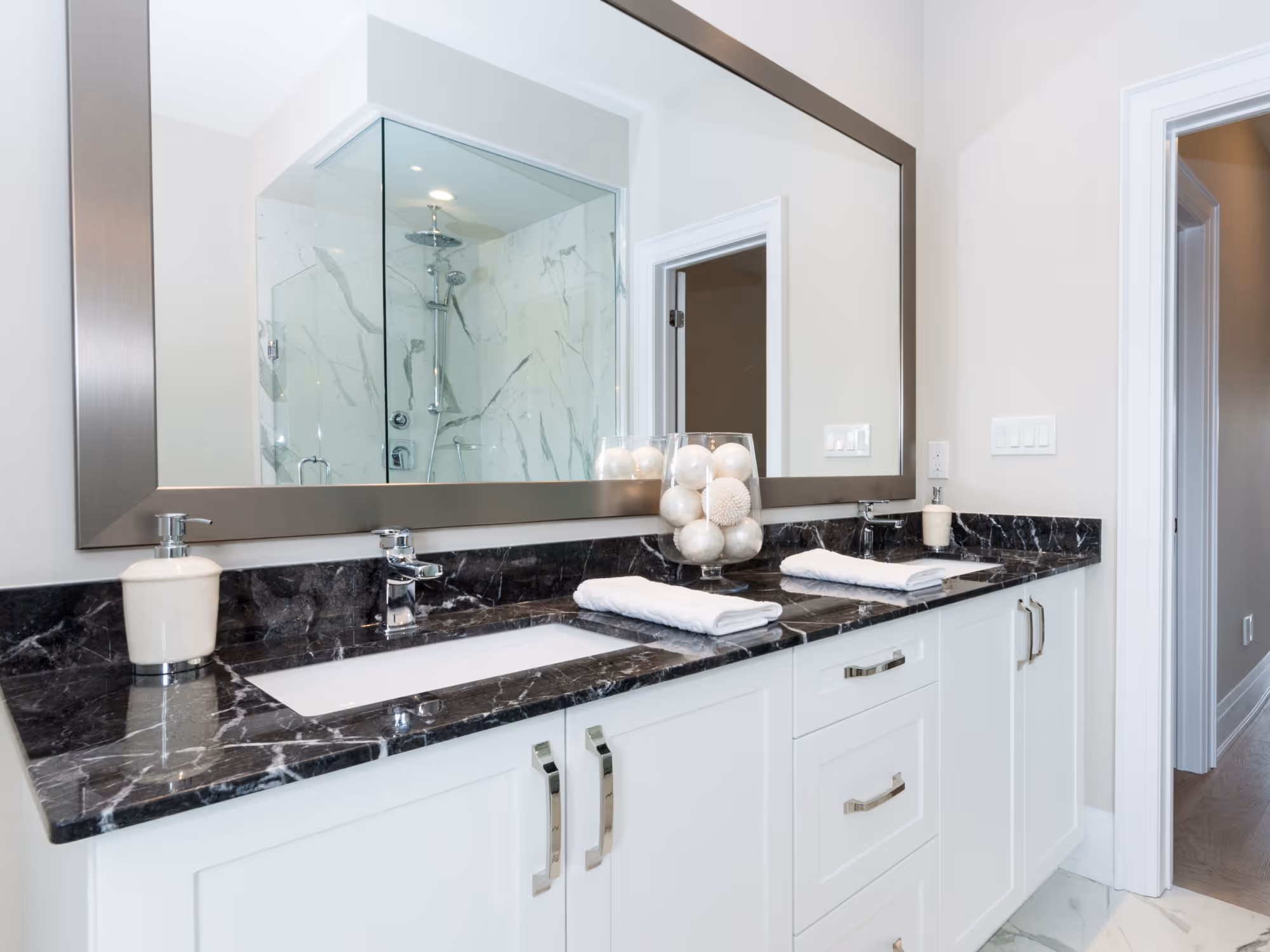Bathroom remodel with double vanity, stone countertop, large mirror, and built-in storage